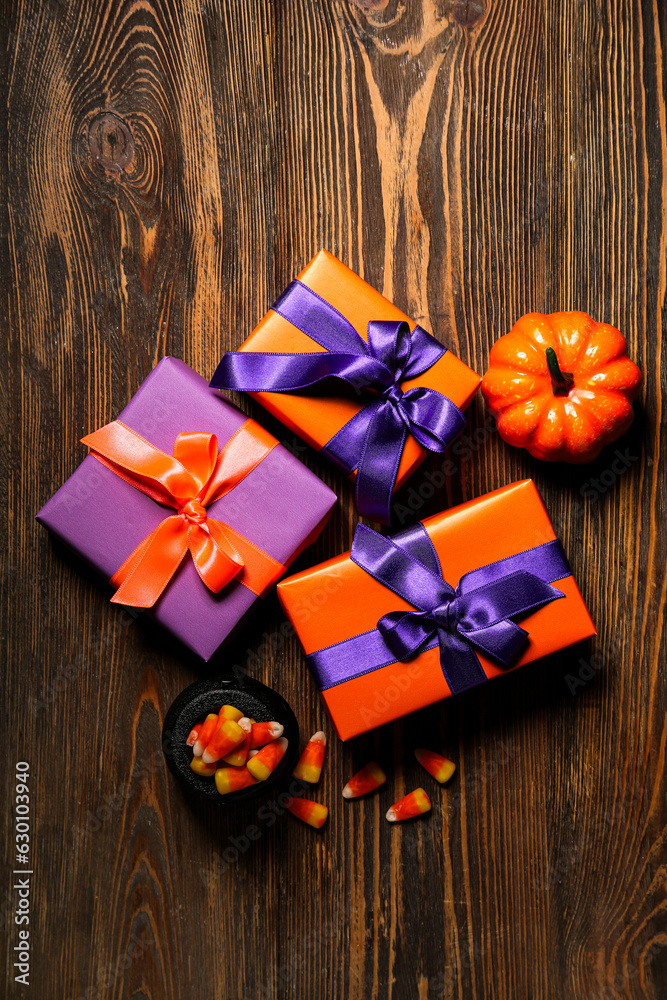Beautiful gift boxes, tasty candy corns and pumpkin for Halloween on wooden background