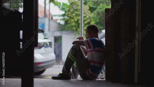 One lonely young black man struggling with life's difficulties leaning on wall by city street covering face in shame and regret. Person going through hardship and emotional suffering