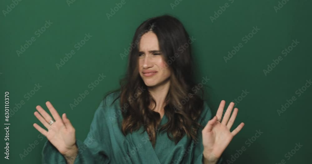 Don't touch me, stay away! Woman look with aversion and wave her hand, no, deny, look by side standing isolated green background.