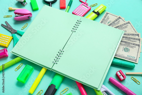 Blank notebook with money and different stationery on turquoise background