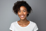 a clean studio portrait of a young african american girl in white t-shirt smiling, grey background.