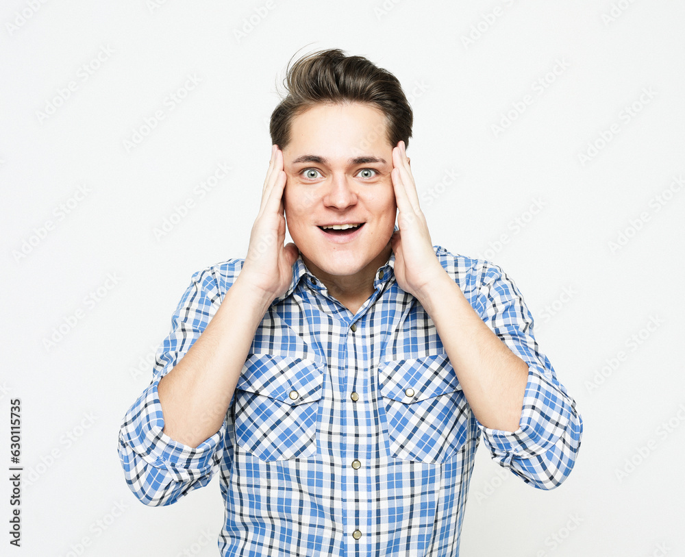 Happy young handsome man gesturing and keeping mouth open Happy young handsome man gesturing and keeping mouth open