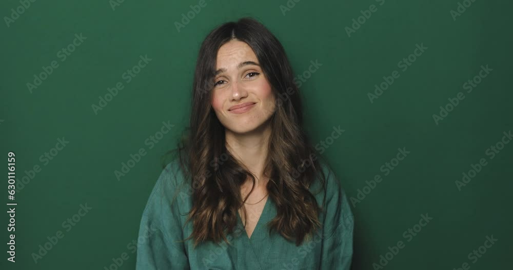 Displeased young woman show shut up gesture standing on green background and looking at camera. Sad woman don't want listen someone, be quieter. Girl makes a gesture with her hands, lowering them. Displeased young woman show shut up gesture standing on green background and looking at camera. Sad woman don't want listen someone, be quieter. Girl makes a gesture with her hands, lowering them.
