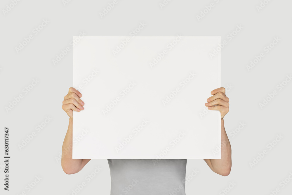 man holding blank white poster isolated on gray background. mockup, space for text man holding blank white poster isolated on gray background. mockup, space for text