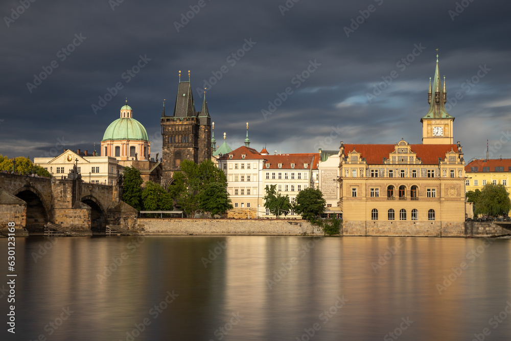charles bridge and embankment illuminated by the sun under heavy rain clouds - just after the rain