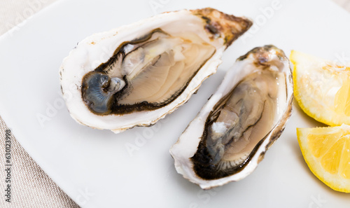 Tasty oysters with lemon on plate top view. High quality photo