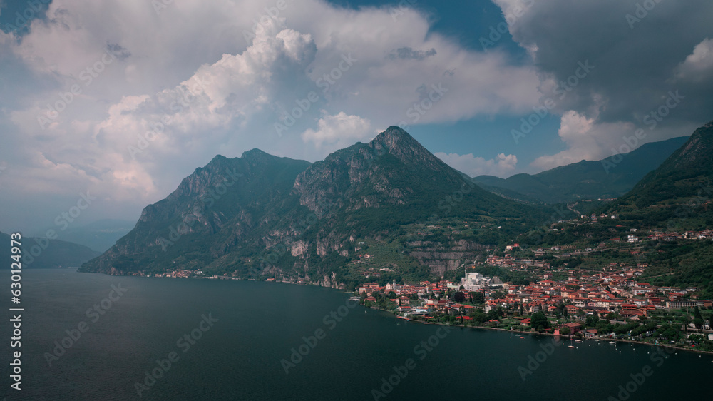 Mountain panorama at Lake Iseo with mountains and village Marone from above during day with blue sky and clouds, Italy