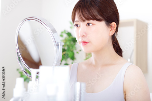 鏡を見ながら顔のスキンケアをする若い女性