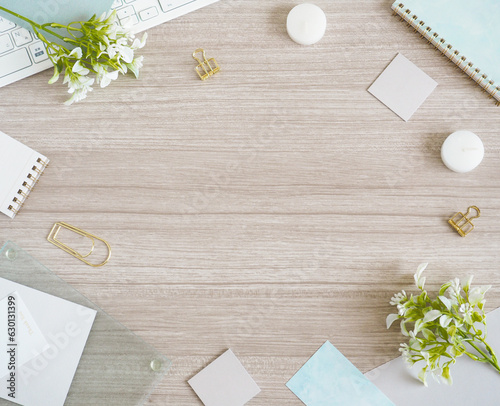 淡い色の木目デスクに白と水色の小物を並べたワークスペースフレーム、さわやかな女性のPCデスクフレーム