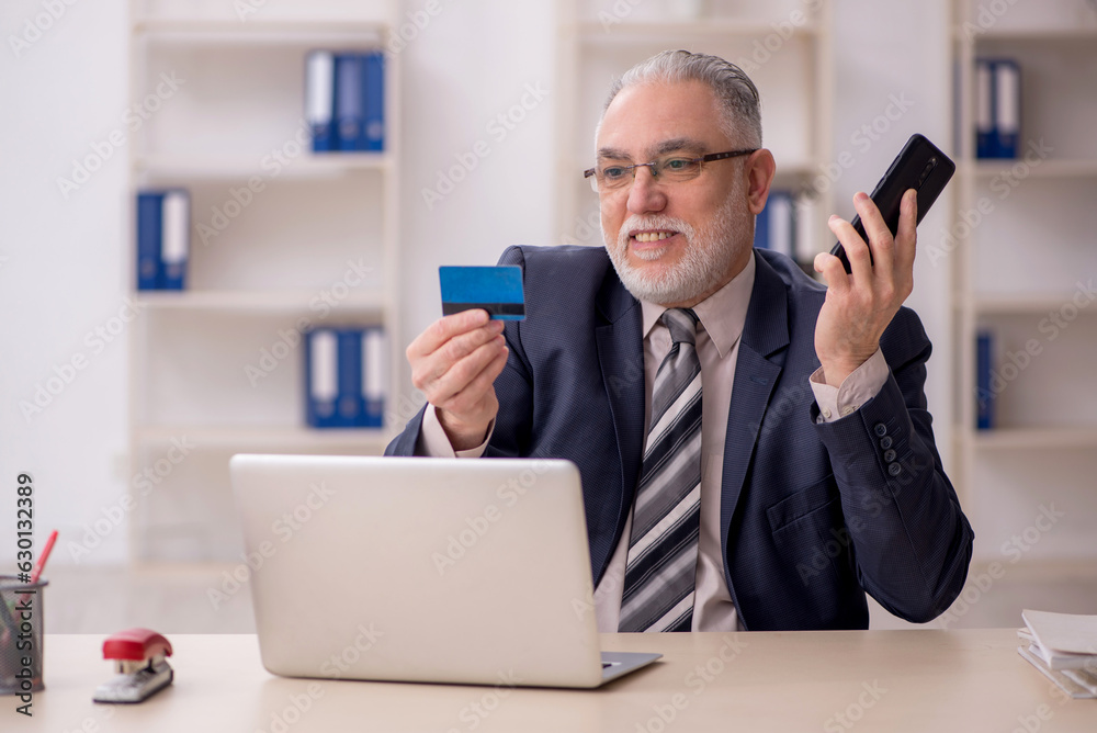 Old male employee holding credit card Old male employee holding credit card