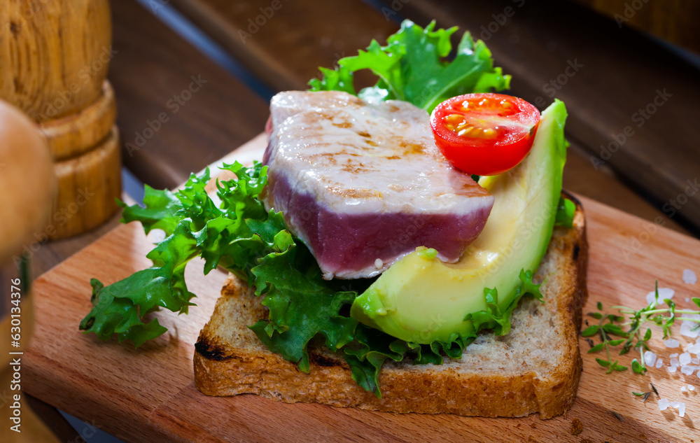 Healthy sandwich with roasted tuna, avocado, lettuce leaves and tomato