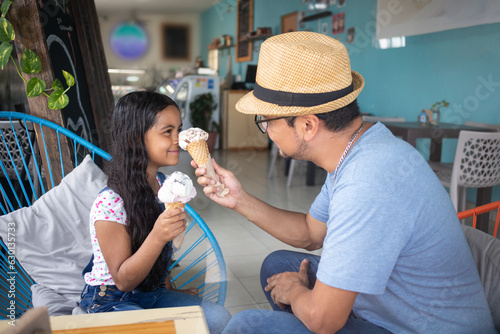 father playing with his daughter while eating gelato, dad putting ice cream on his child girl having fun