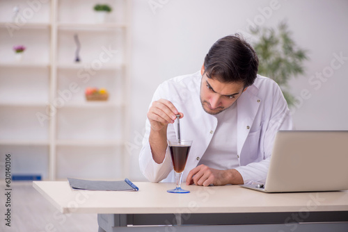Young male chemist examining soft drink