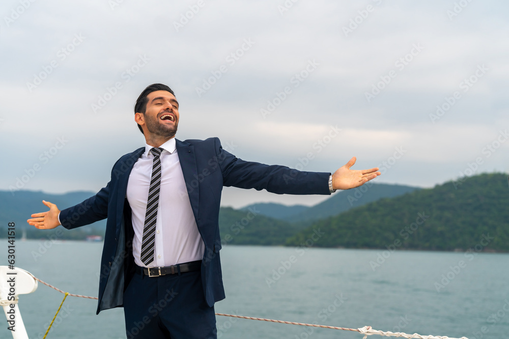 Confident Caucasian businessman raise hand up with shouting celebrating for global business success while travel on luxury private catamaran boat yacht sailing in the ocean on summer holiday vacation