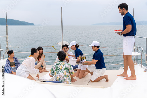 Yacht crew serving fruit and champagne to passenger tourist during celebration party travel on luxury catamaran boat yacht sailing in the ocean on summer vacation. Cruise ship service occupation.