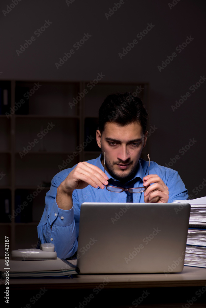 Young male employee working late in the office