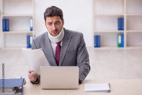 Young male employee after car accident sitting in the office