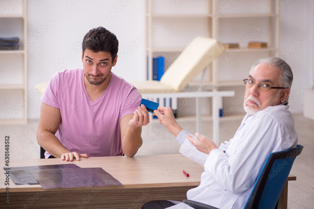 Fototapeta premium Young male patient visiting old male doctor