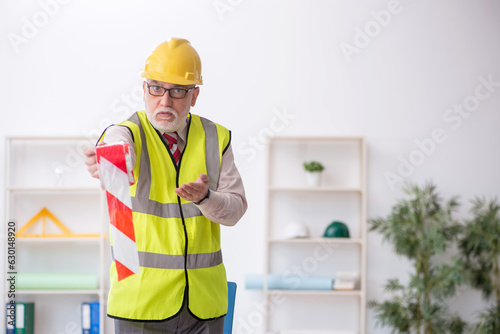Old male architect holding caution tape