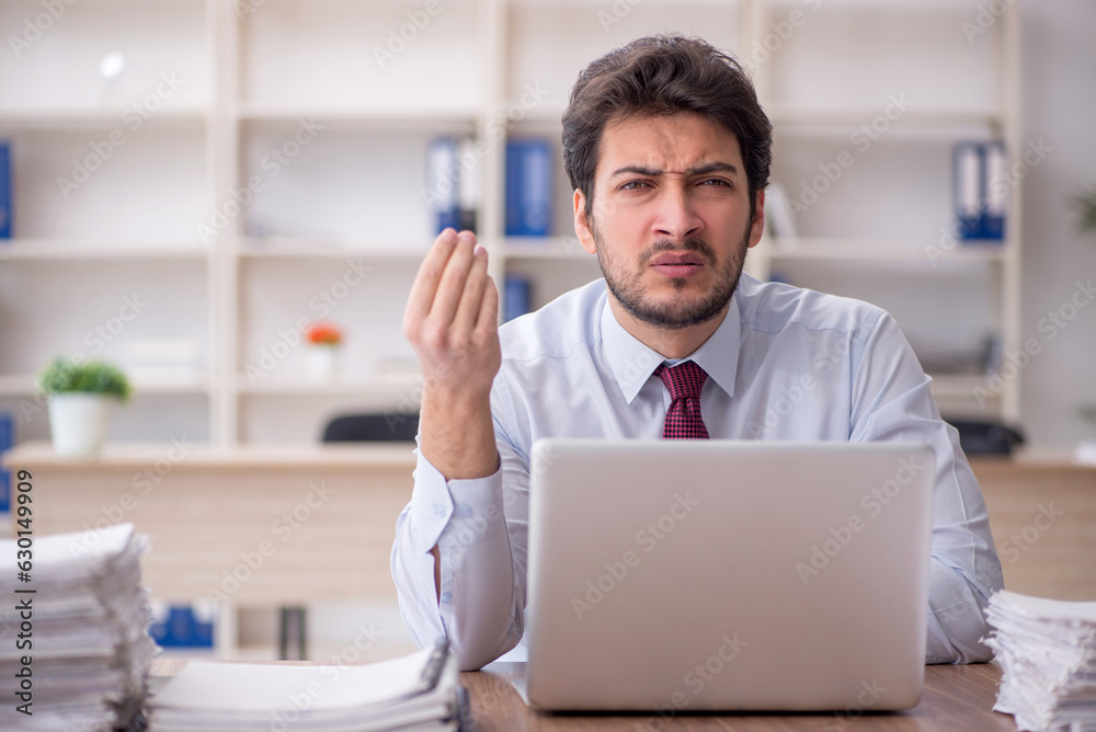 Young male employee and too much work in the office Young male employee and too much work in the office