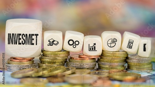 Business and finance concept. On the background of coins and banknotes, dice with the inscription - investment