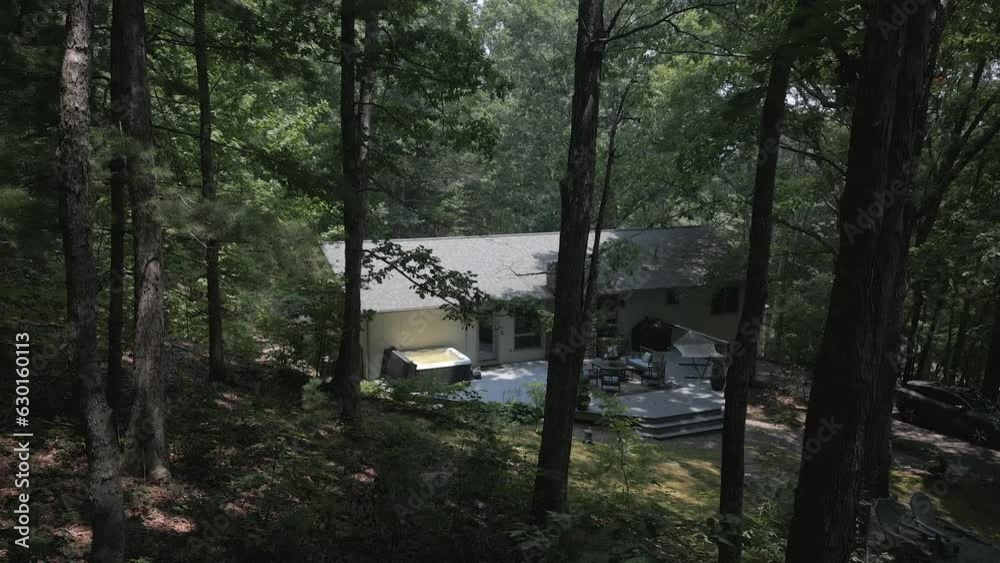 POV: Rural house on forested country hillside seen through green trees POV: Rural house on forested country hillside seen through green trees