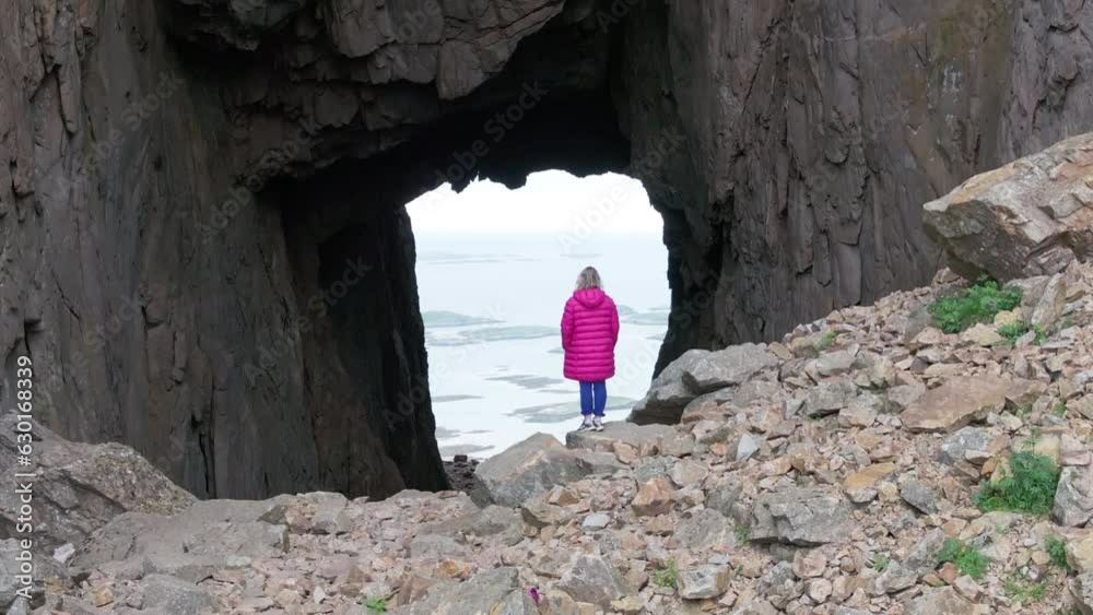Drone reveal majestic hole through Torghatten mountain with woman in foreground Drone reveal majestic hole through Torghatten mountain with woman in foreground