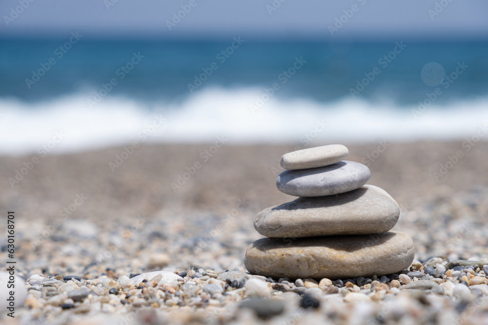 Fototapeta premium Round stones lie on top of each other in a column on the seashore on a sunny summer day. The concept of order and tranquility