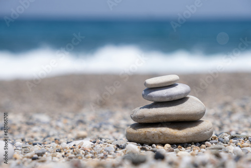 Round stones lie on top of each other in a column on the seashore on a sunny summer day. The concept of order and tranquility