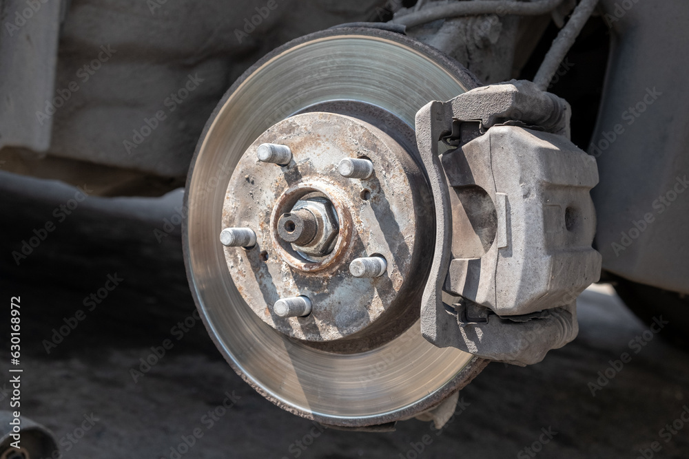 Disc brake of the vehicle for repair, in process of new tire replacement. Car brake repairing in garage. Replacement of brake pads. Suspension of car for maintenance brakes and shock absorber systems.