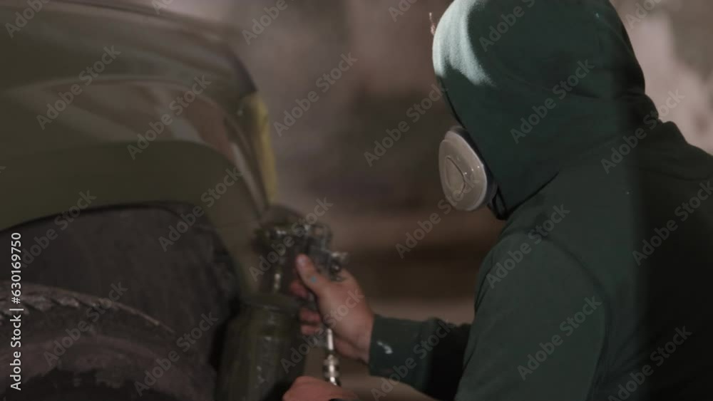 Wearing respirator, Respirator masks, Mask wearing. Respirator-equipped man employing spray gun to coat vehicle. Wearing respirator, Respirator masks, Mask wearing. Respirator-equipped man employing spray gun to coat vehicle.