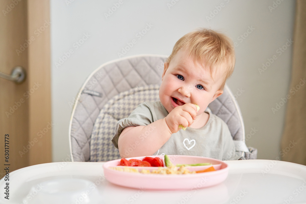 Cute child eats healthy food pasta and vegetables steamed,. Portraits of a cute 10 months old baby girl. The baby sitting in a special high chair for babies. Cute child eats healthy food pasta and vegetables steamed,. Portraits of a cute 10 months old baby girl. The baby sitting in a special high chair for babies.