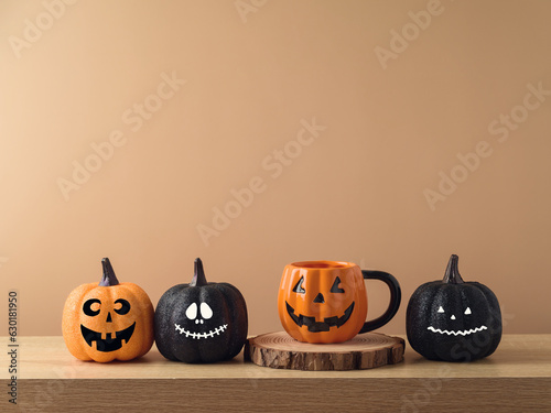 Halloween holiday concept with jack o lantern coffee cup and funny glitter pumpkin decoration on wooden table over modern  background