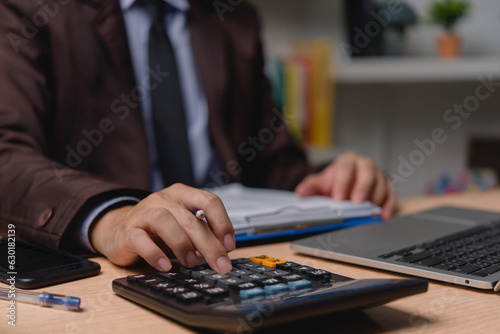 Businessman working on laptop and accounting financial marketing report document investment paperwork. hands of accountant using calculator to calculate tax refund economy.