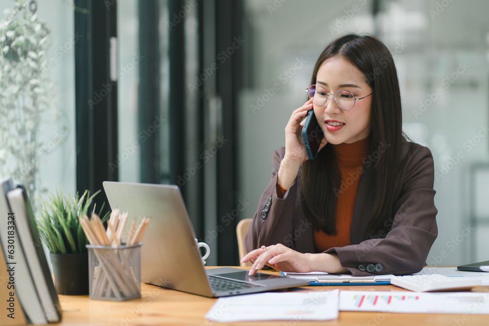 A portrait of a smiling, young, beautiful, professional, and confident millennial Asian businesswoman using a digital tablet to analyze sales data at a modern office. A portrait of a smiling, young, beautiful, professional, and confident millennial Asian businesswoman using a digital tablet to analyze sales data at a modern office.