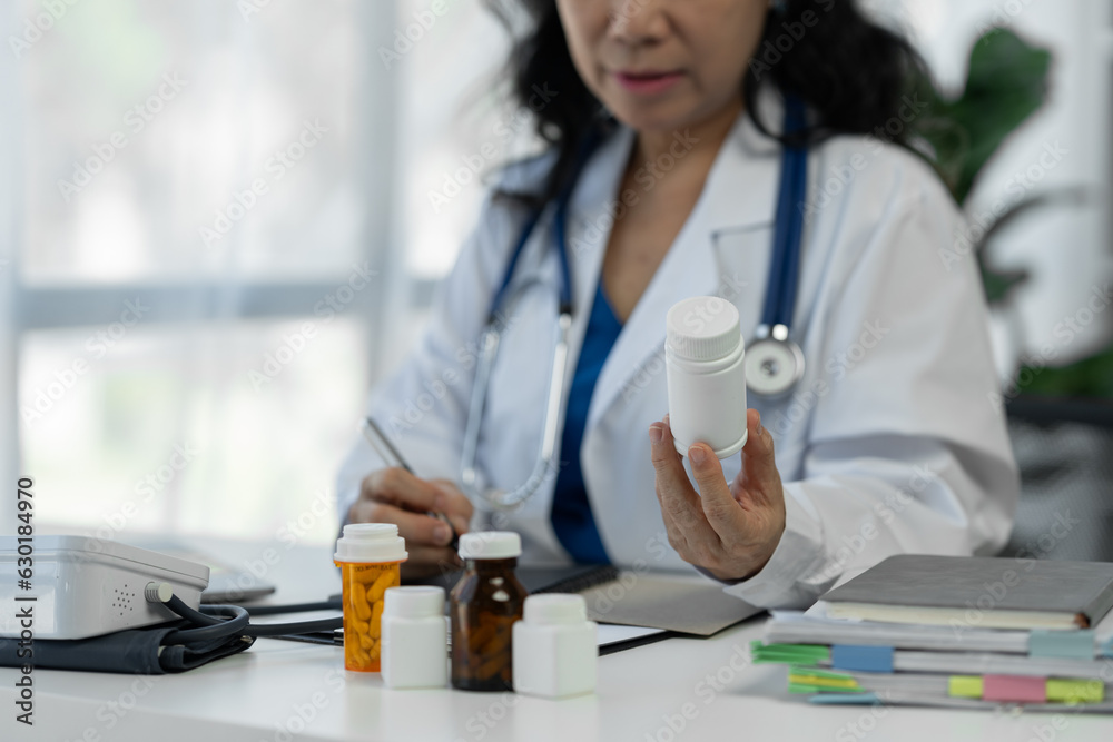 Senior female medical staff in the clinic wearing a doctor's white coat is examining Record patient medication information Medical concept, research, guideline, treatment, medicine Senior female medical staff in the clinic wearing a doctor's white coat is examining Record patient medication information Medical concept, research, guideline, treatment, medicine