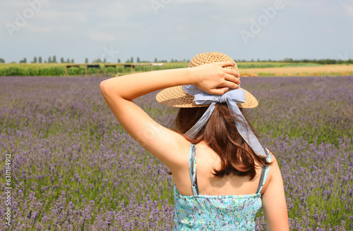 Young girl with straw boater in the wide field of lavender flowers