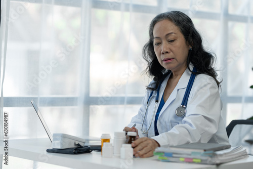 Senior female medical staff in the clinic wearing a doctor's white coat is examining Record patient medication information Medical concept, research, guideline, treatment, medicine