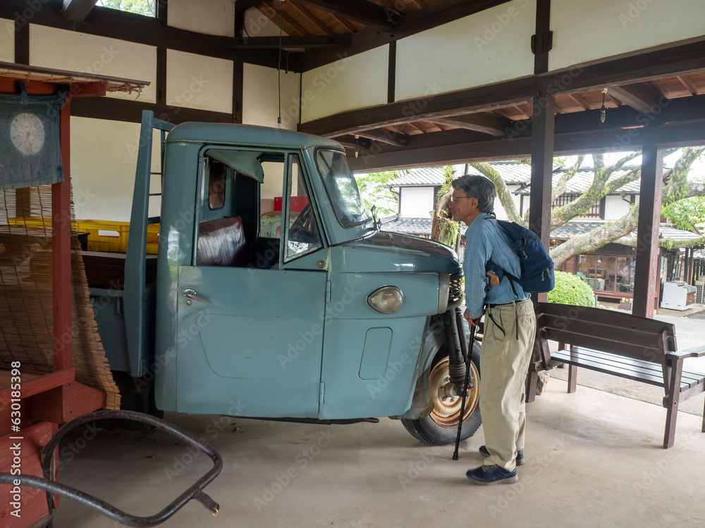 A senior man looking at old Japanese auto tricycle A senior man looking at old Japanese auto tricycle