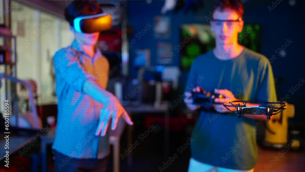 Young engineers with VR virtual reality headset controlling fliying drone in research laboratory, slow motion