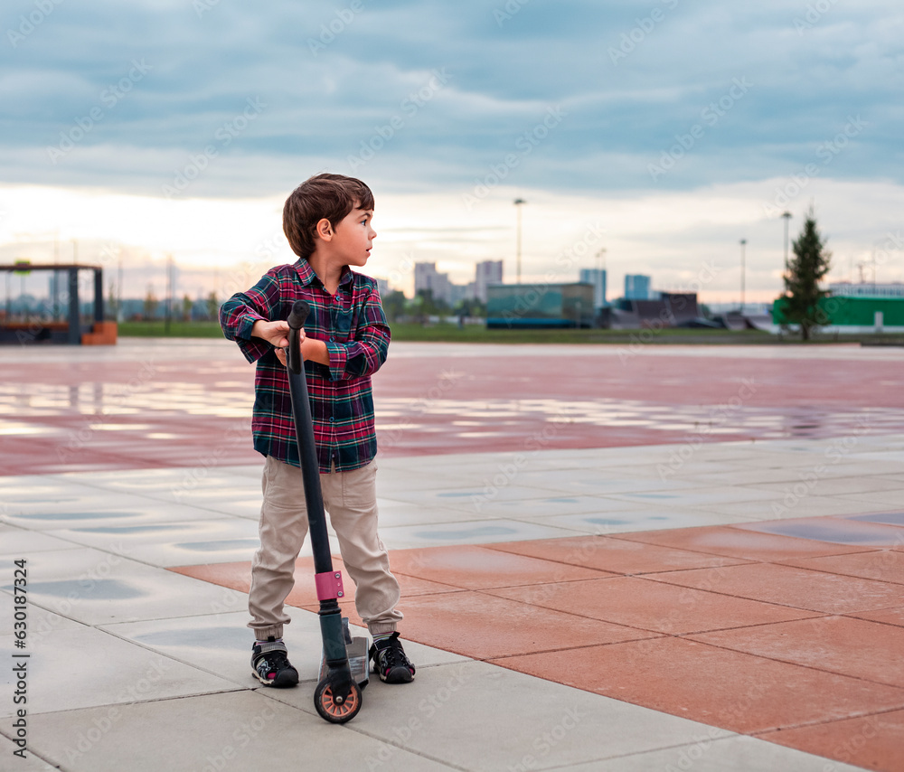 Little boy in checkered shirt riding scooter on the playground Little boy in checkered shirt riding scooter on the playground