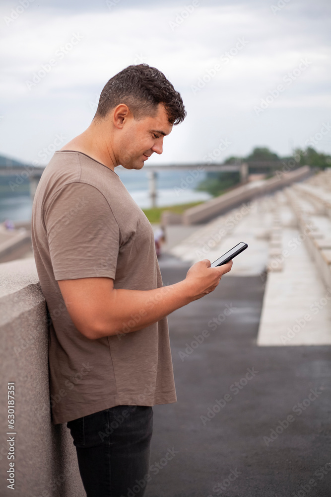 Young man using a mobile phone on the embankment of the river