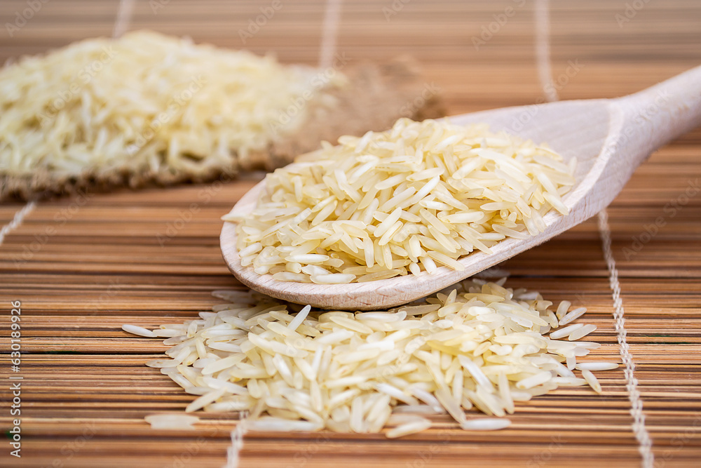 A wooden spoon filled with rice on top of a bamboo mat A wooden spoon filled with rice on top of a bamboo mat