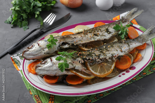 Mullet baked with vegetables, spices and lemon served on a plate