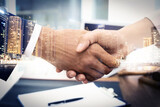 Deal or partnership concept. Double exposure with cityscape and photo of businesspeople shaking hands