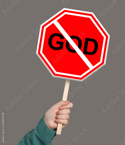 Atheism concept. Woman holding prohibition sign with crossed out word God on color background photo