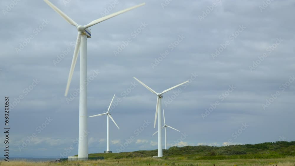 Windmills on windy coastline rotating against bright cloudy summer sky. Half speed slow motion. Windmills on windy coastline rotating against bright cloudy summer sky. Half speed slow motion.