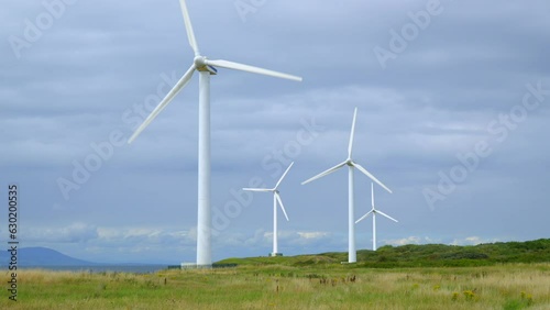Wallpaper Mural Windmills on coastline with mountains in distance on cloudy bright summer day. Half speed slow motion. Torontodigital.ca