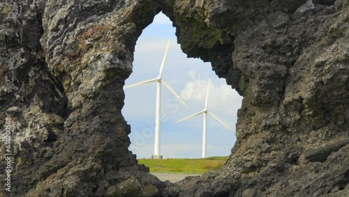 Windmills rotating framed through coastal rock hole formation. Half speed slow motion. photo