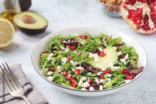 A plate with green rocket salad with pomegranate and avocado